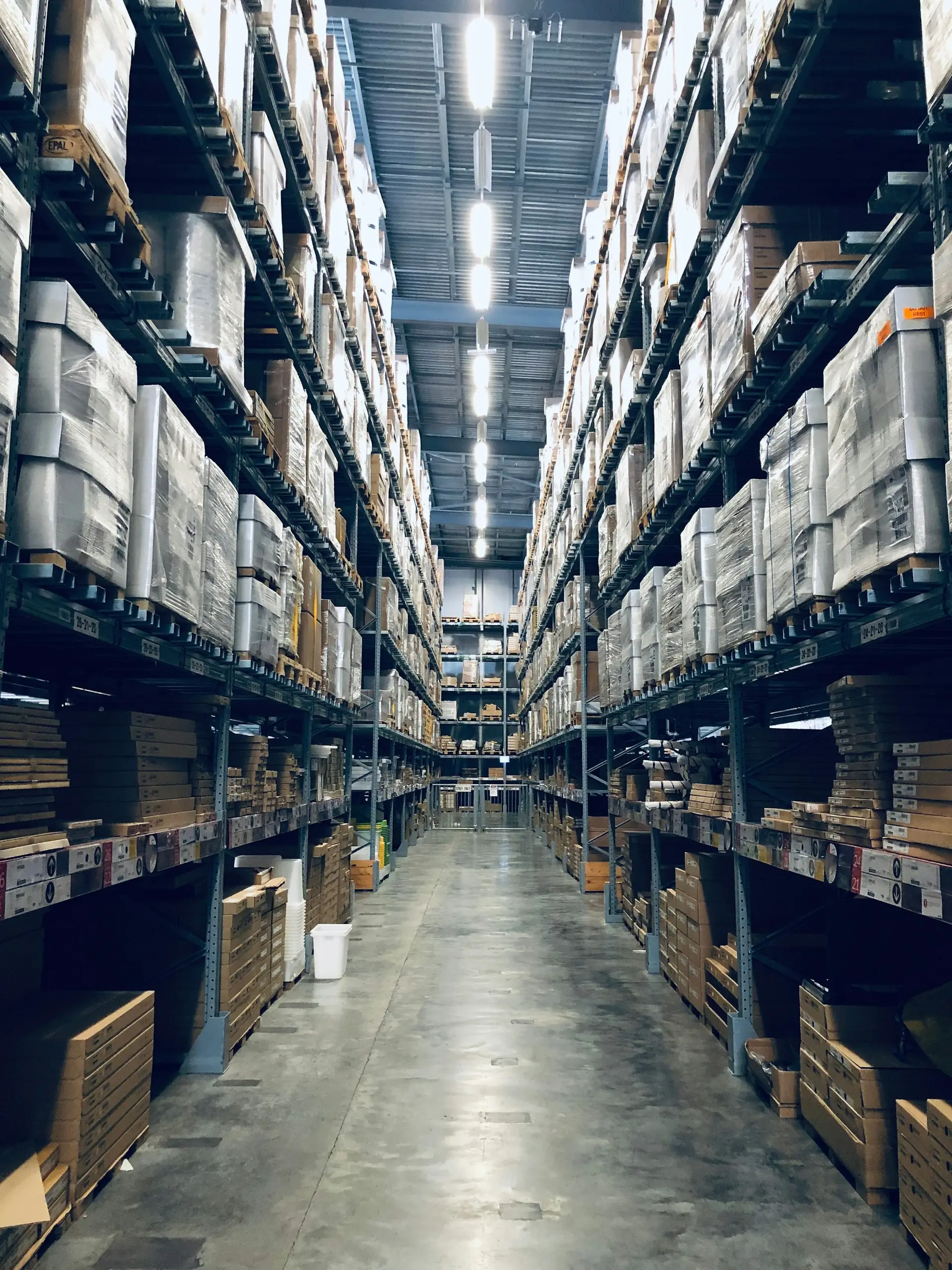 A long warehouse aisle with racking full of palletised goods